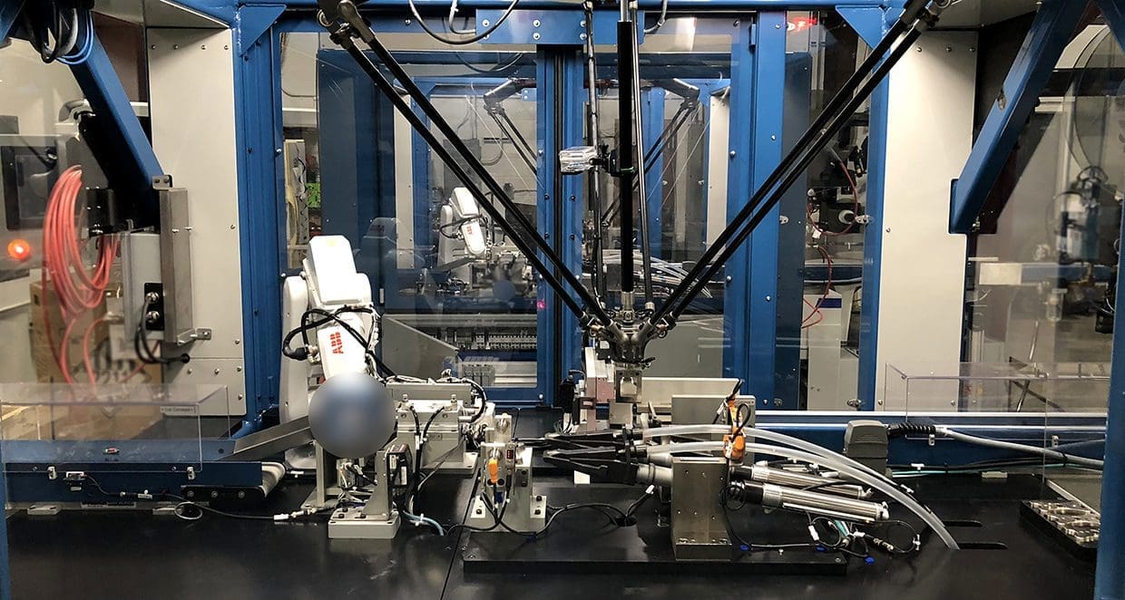 Robotic pick-and-place cell inside manufacturing station