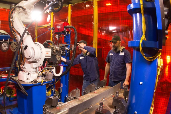 Technicians working beside robotic assembly cell