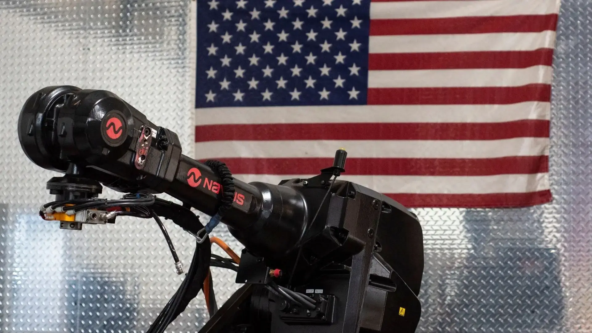 Black robot manipulator arm beside American flag