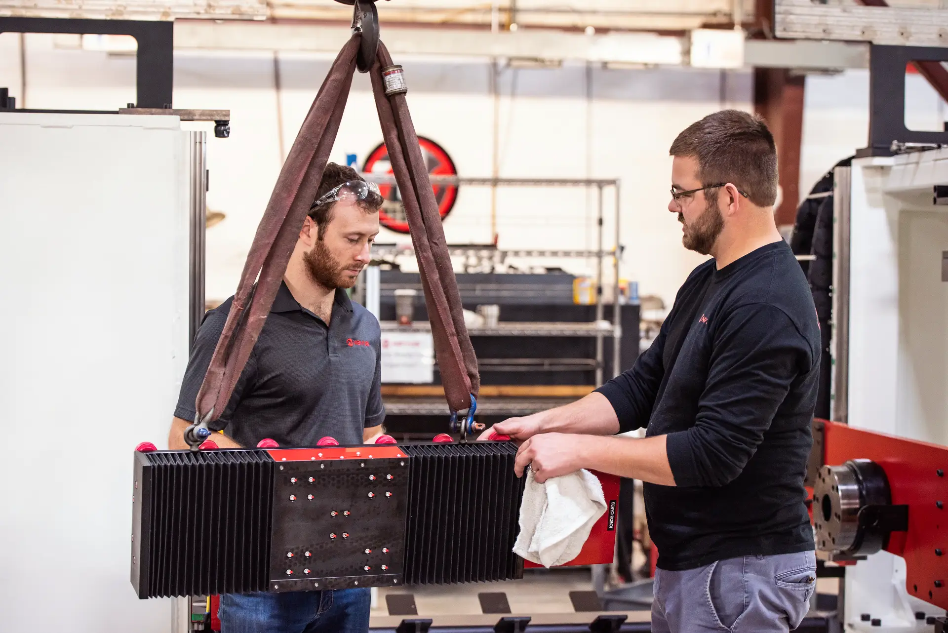 Two workers handling industrial equipment together.