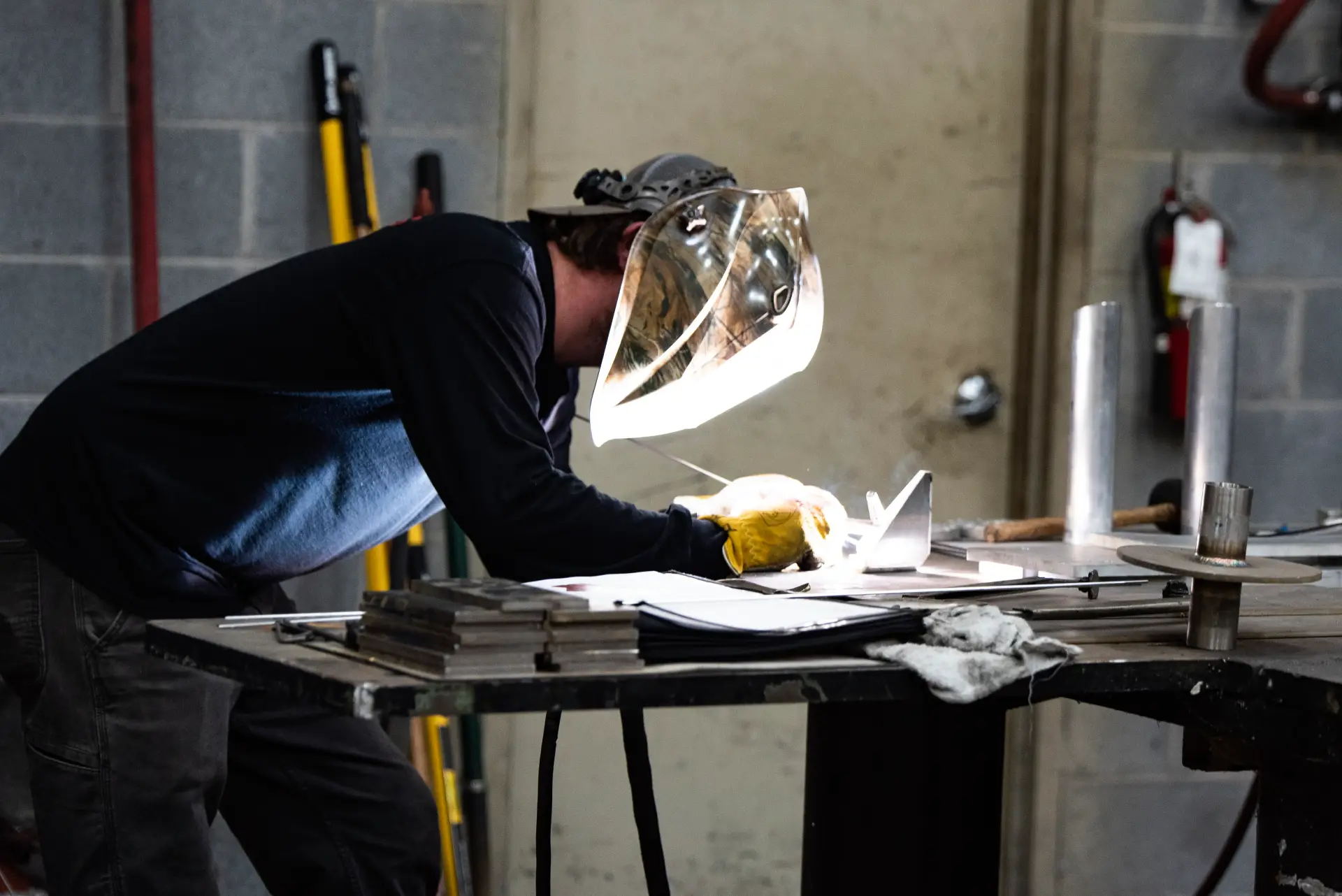 Welder working with protective gear and tools.