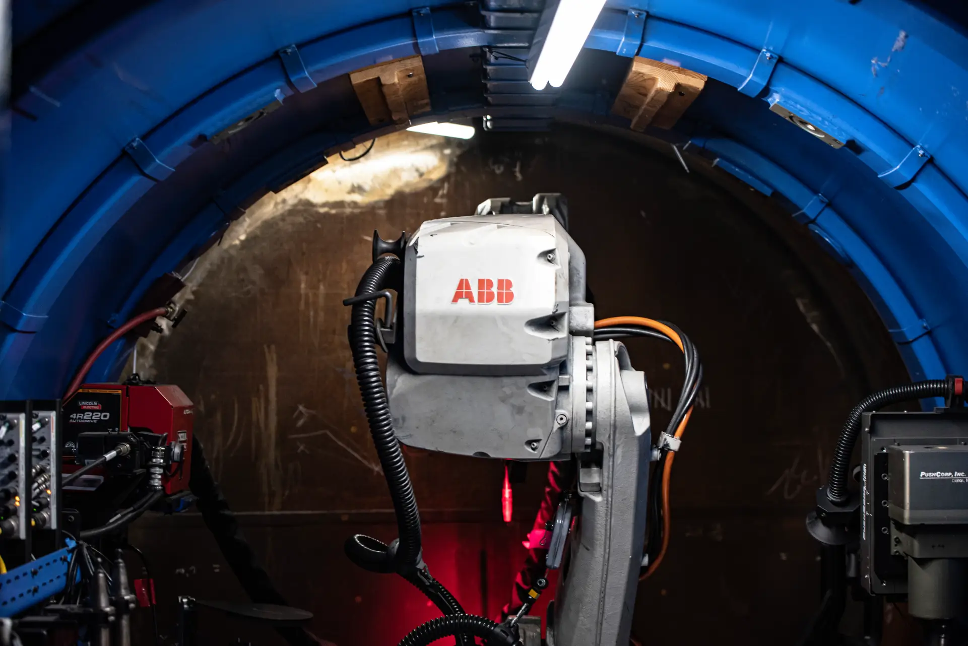 Industrial robot inside blue tunnel, dimly lit.